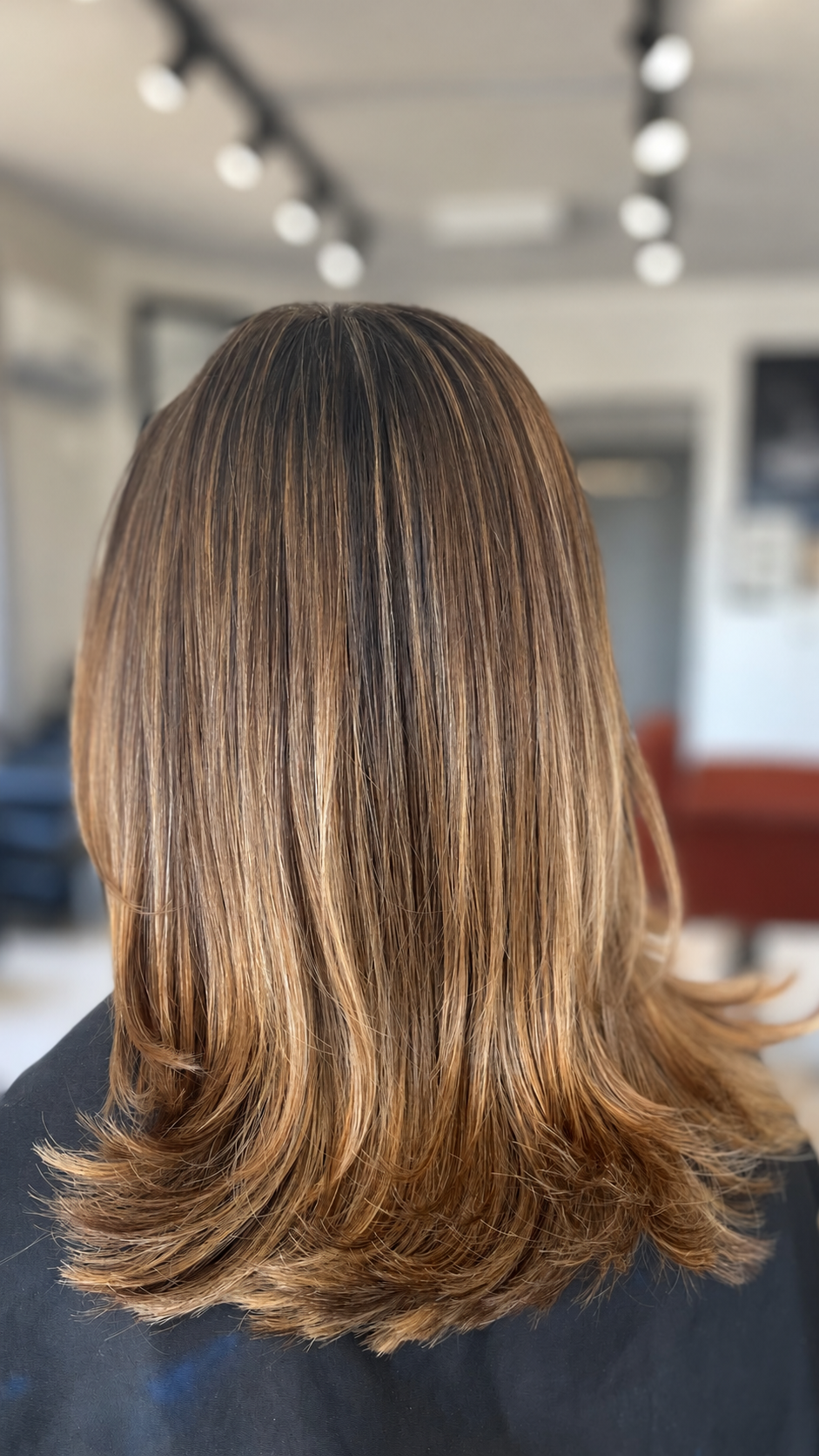 Cabelo castanho liso com reflexos dourados, visto de costas