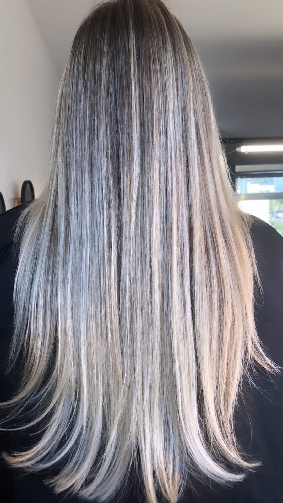 Cabelo loiro longo e liso com mechas frias, visto de costas