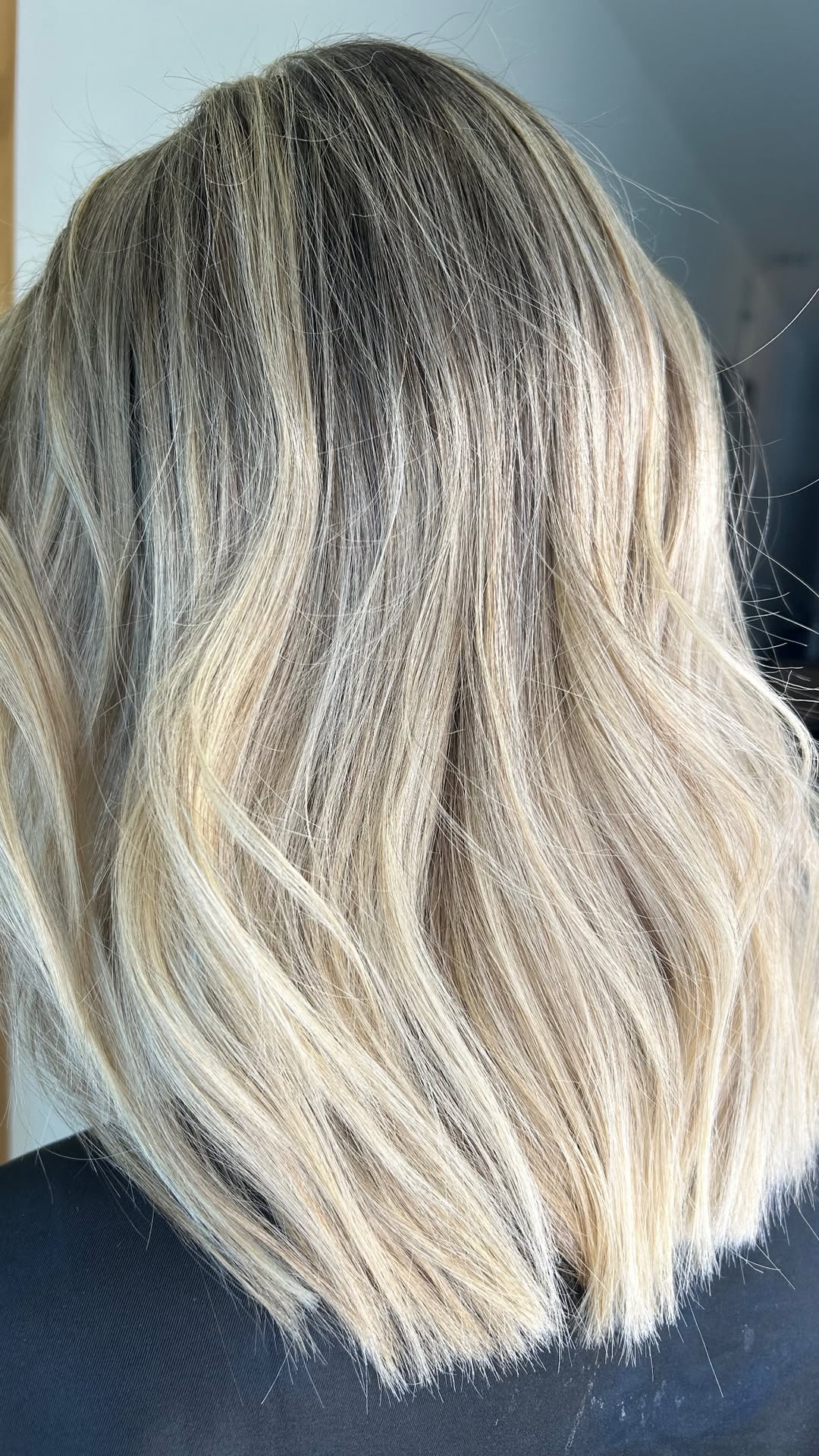 Cabelo loiro médio com fios iluminados, visto de costas