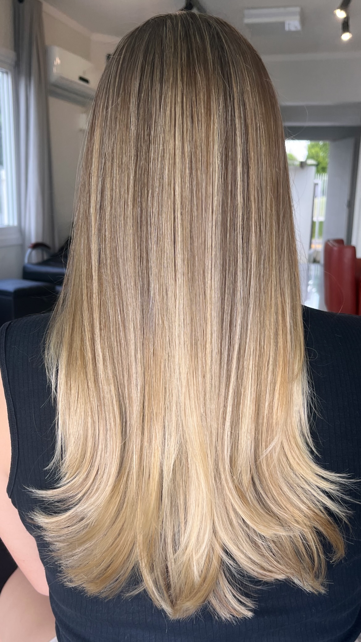 Cabelo loiro liso com pontas em camadas, visto de costas